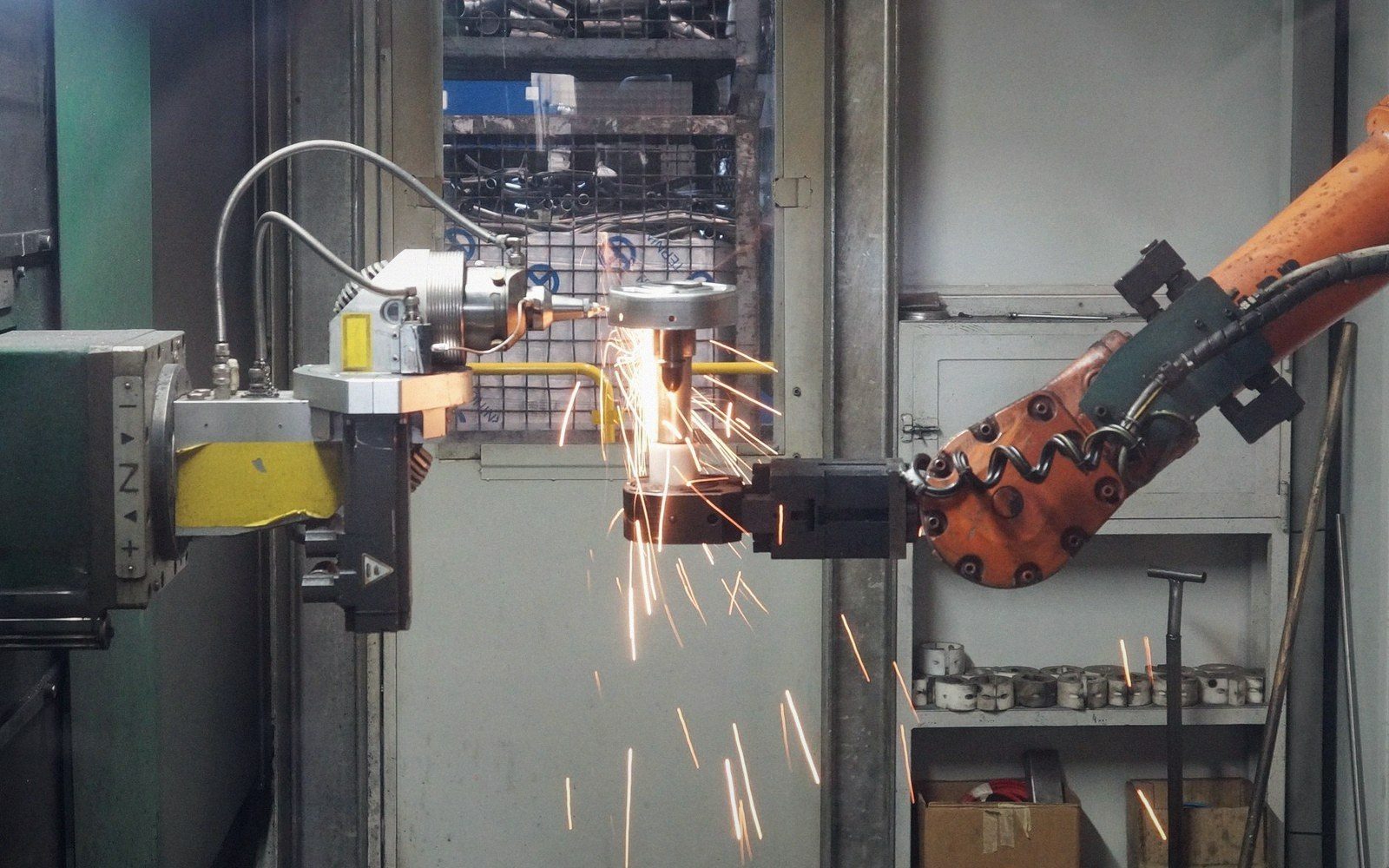 An industrial robotic arm welding metal, throwing bright orange sparks in a workshop